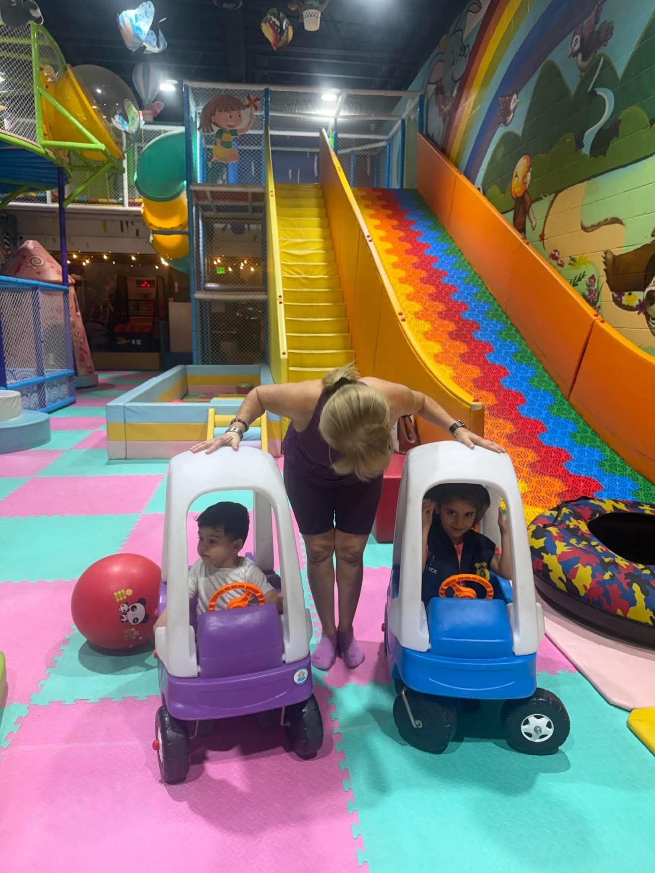 A child explores movement and play with supportive adults nearby.