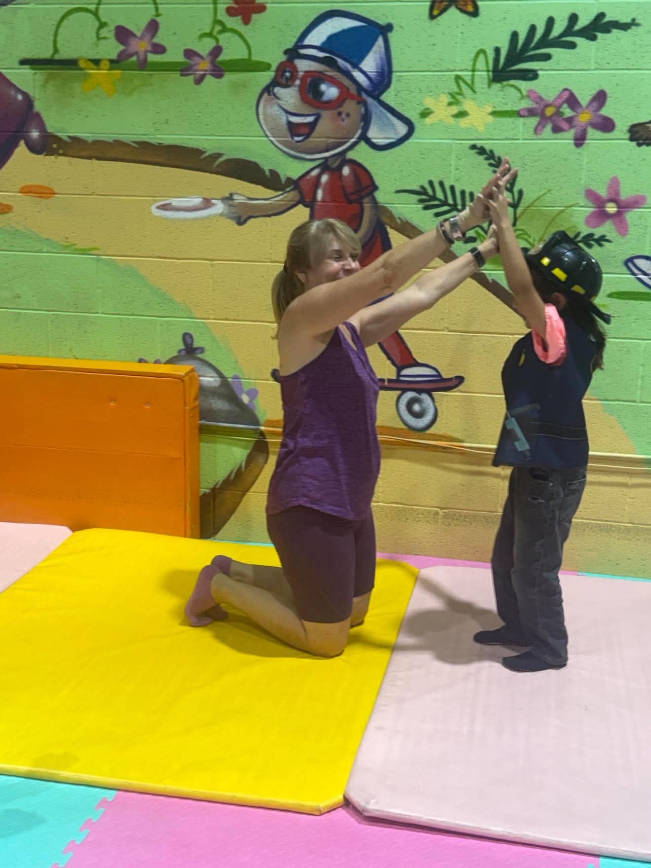 A child participates in a class activity with a caregiver present.